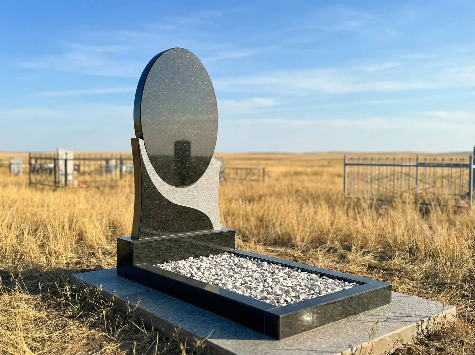 Строгий черный гранитный памятник на могилу, установленный на фоне гор, вид спереди.